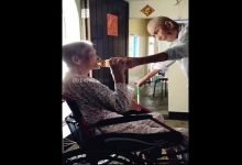 elderly husband gives water to his wife-min