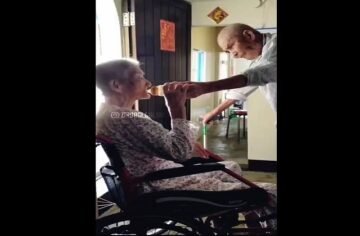 elderly husband gives water to his wife-min