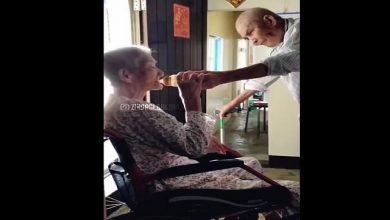 elderly husband gives water to his wife-min